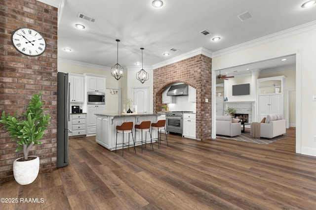 40400 Abby James Rd, Prairieville, LA 70769 - kitchen with stainless steel appliances, wall chimney range hood, a breakfast bar area, dark wood-style floors, and white cabinets