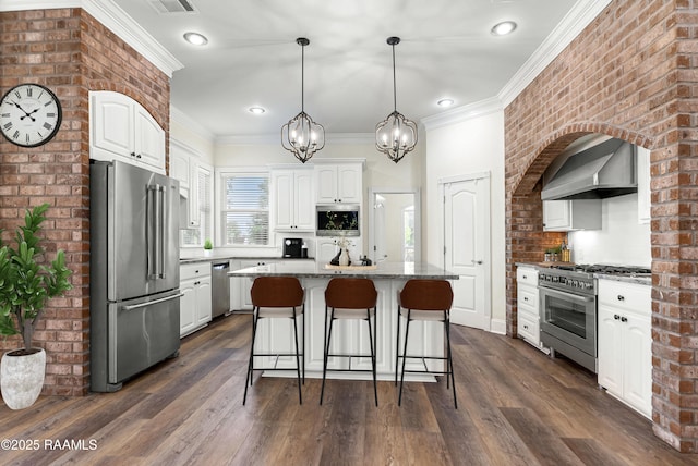 40400 Abby James Rd, Prairieville, LA 70769 - kitchen featuring high quality appliances, wall chimney range hood, white cabinets, a breakfast bar, and light stone counters