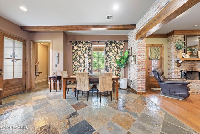124 Edmund Ln, Eunice, LA 70535 - dining space with stone tile flooring, beamed ceiling, baseboards, a brick fireplace, and stairway