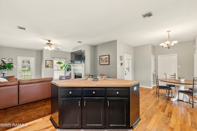 107 Westpointe Cir, Lafayette, LA 70506 - kitchen with butcher block counters, a tile fireplace, light wood-style flooring, open floor plan, and a chandelier