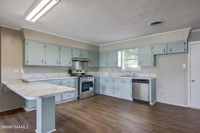 650 Juanita St, Eunice, LA 70535 - kitchen with appliances with stainless steel finishes, a sink, under cabinet range hood, a peninsula, and dark wood-style flooring