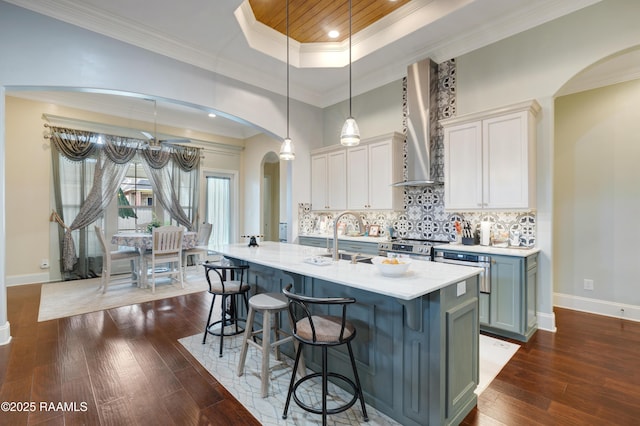 106 Camry Dr, Lafayette, LA 70503 - kitchen featuring wall chimney range hood, arched walkways, dark wood-type flooring, light countertops, and ornamental molding