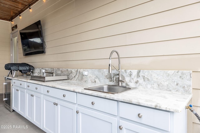105 Hazy River Way, Lafayette, LA 70508 - kitchen with a sink, beverage cooler, white cabinetry, wood walls, and light stone countertops