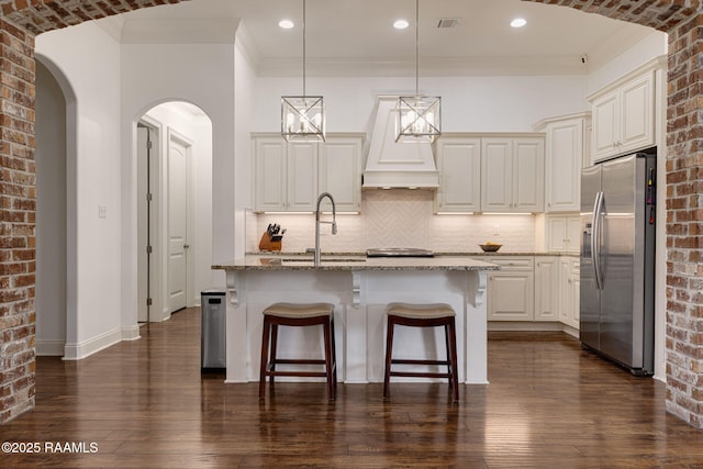 105 Hazy River Way, Lafayette, LA 70508 - kitchen with stainless steel fridge, light stone counters, a sink, a breakfast bar, and decorative backsplash