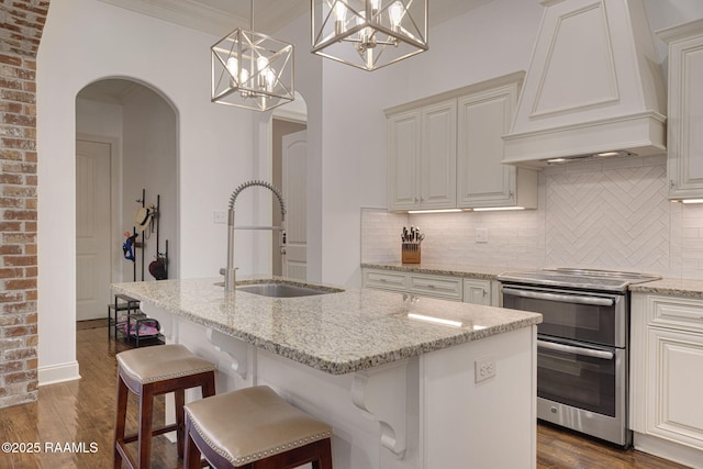 105 Hazy River Way, Lafayette, LA 70508 - kitchen with custom range hood, double oven range, a sink, arched walkways, and light stone counters
