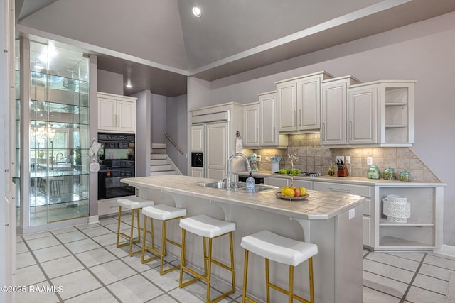 102 Capilano Ln, Broussard, LA 70518 - kitchen featuring open shelves, light tile patterned flooring, tasteful backsplash, tile counters, and a breakfast bar area