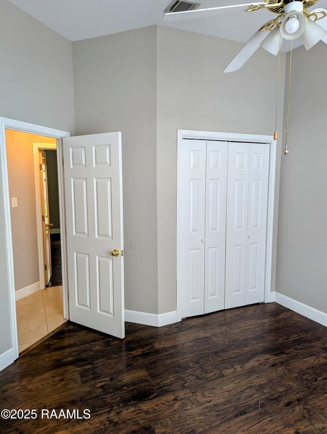 103 E Weeks Dr, Youngsville, LA 70592 - unfurnished bedroom with baseboards, dark wood-style floors, a towering ceiling, a closet, and ceiling fan