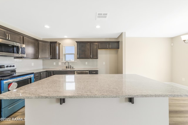 119 Sandstone Ave, Scott, LA 70583 - kitchen featuring stainless steel appliances, a sink, dark brown cabinets, a kitchen breakfast bar, and recessed lighting