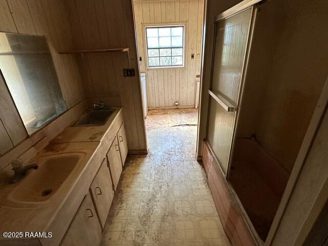 18711 La Highway 35, Abbeville, LA 70510 - bathroom featuring wooden walls, a shower with door, double vanity, and tile patterned floors