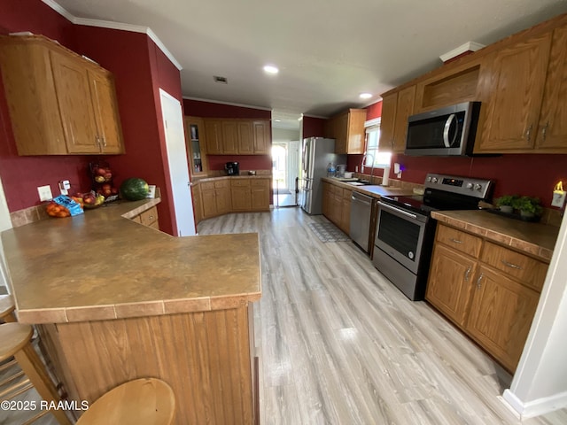119 Opus Ln, Lafayette, LA 70506 - kitchen featuring appliances with stainless steel finishes, light wood finished floors, crown molding, a peninsula, and a sink