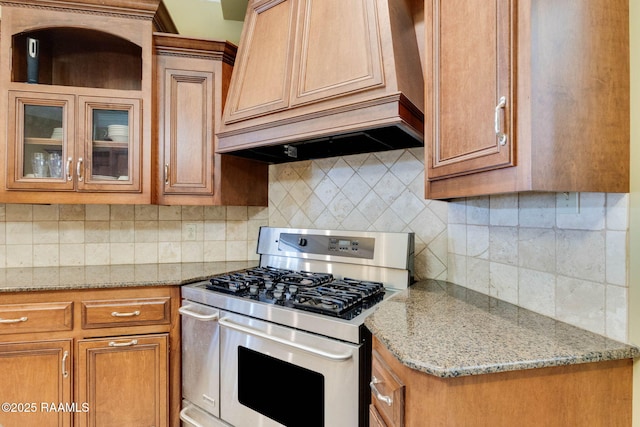 605 Terrell Ct, New Iberia, LA 70563 - kitchen featuring stainless steel range with gas stovetop, brown cabinetry, tasteful backsplash, and glass insert cabinets