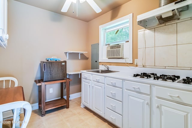 2424 Vista Dr, Opelousas, LA 70570 - kitchen with under cabinet range hood, a sink, white gas stovetop, a ceiling fan, and white cabinets