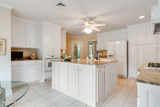 2424 Vista Dr, Opelousas, LA 70570 - kitchen with white appliances, light tile patterned flooring, white cabinets, a ceiling fan, and a center island with sink
