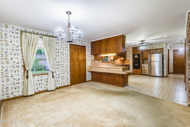 138 Cypress Dr, Opelousas, LA 70570 - kitchen featuring freestanding refrigerator, wallpapered walls, brown cabinets, a chandelier, and a peninsula