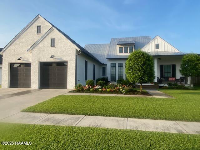 207 Bronze Palm Way, Youngsville, LA 70592 - modern farmhouse style home with a front yard, concrete driveway, an attached garage, metal roof, and a standing seam roof