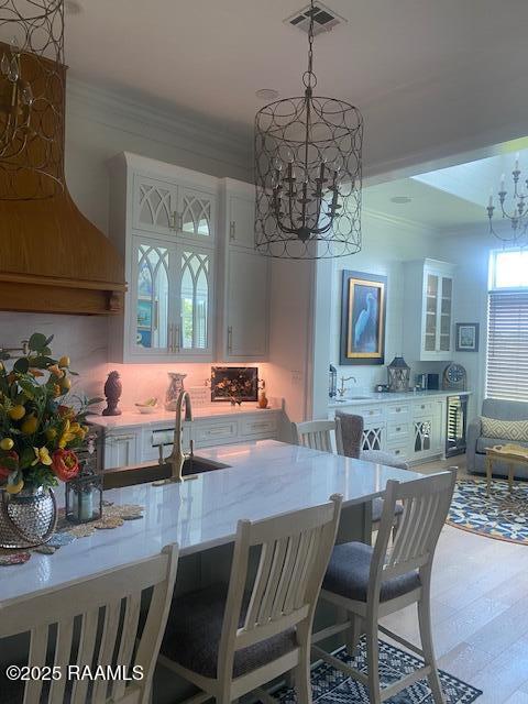 207 Bronze Palm Way, Youngsville, LA 70592 - kitchen with a chandelier, ornamental molding, white cabinetry, a breakfast bar area, and a sink