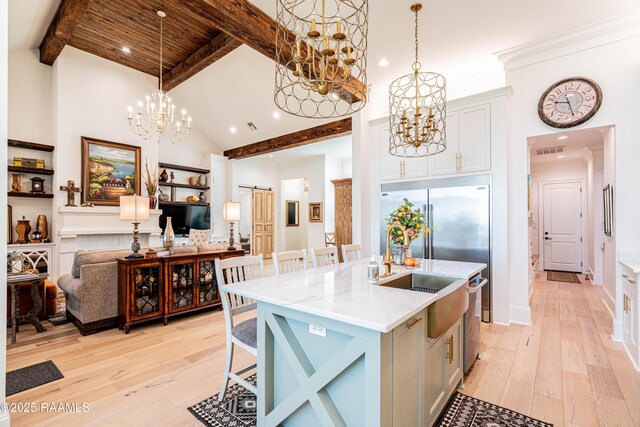 207 Bronze Palm Way, Youngsville, LA 70592 - kitchen featuring a chandelier, light wood finished floors, an island with sink, beam ceiling, and light stone countertops