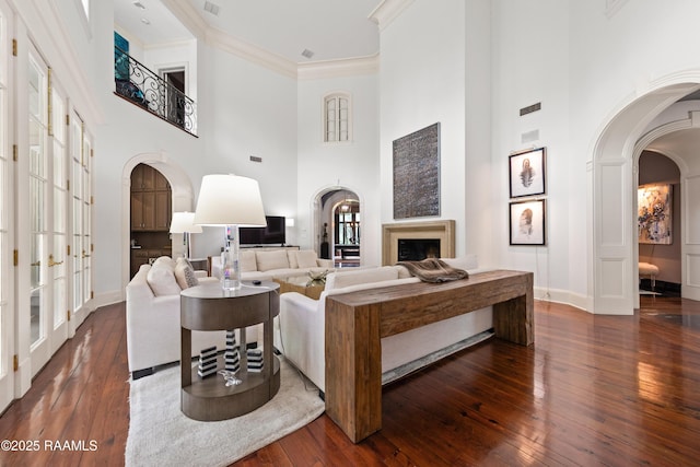 12425 N Marcus Rd, Abbeville, LA 70510 - living area featuring arched walkways, a high ceiling, hardwood / wood-style flooring, a fireplace, and baseboards
