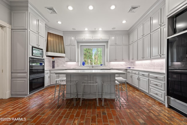 12425 N Marcus Rd, Abbeville, LA 70510 - kitchen featuring light countertops, stainless steel microwave, custom range hood, a breakfast bar, and recessed lighting