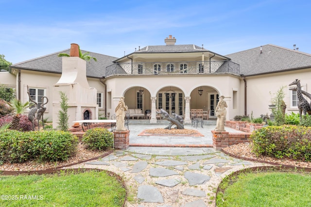 12425 N Marcus Rd, Abbeville, LA 70510 - back of house with a balcony, stucco siding, a patio, a chimney, and a shingled roof