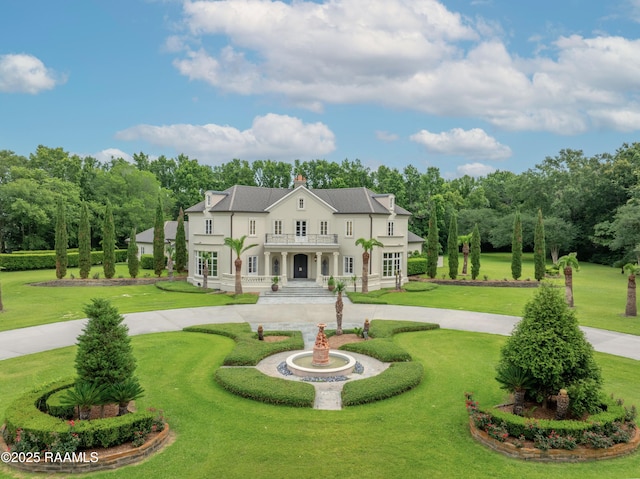 12425 N Marcus Rd, Abbeville, LA 70510 - rear view of house with a balcony, curved driveway, a lawn, stucco siding, and view of wooded area
