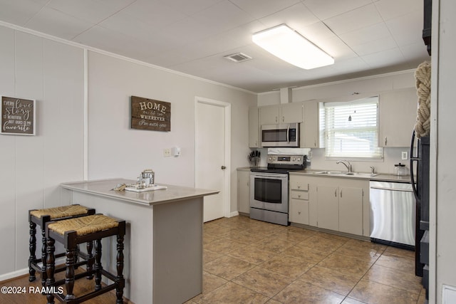 1037 Joe Kidder Rd, Arnaudville, LA 70512 - kitchen featuring stainless steel appliances, a sink, ornamental molding, light countertops, and a kitchen bar