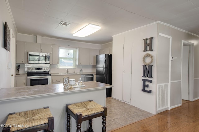 1037 Joe Kidder Rd, Arnaudville, LA 70512 - kitchen with appliances with stainless steel finishes, a peninsula, light countertops, a sink, and a kitchen breakfast bar