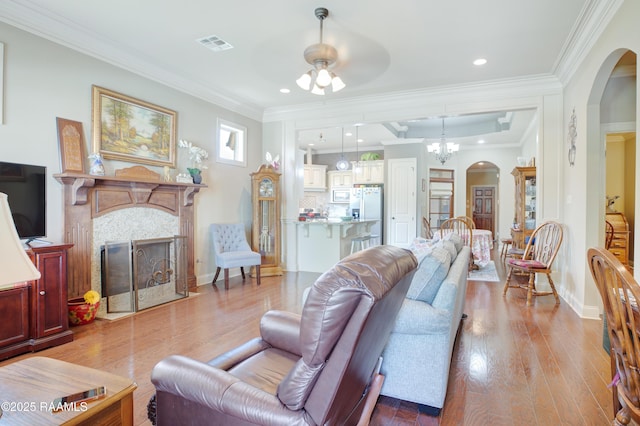111 Grand Pointe Blvd, Lafayette, LA 70508 - living room with ceiling fan, a fireplace with flush hearth, arched walkways, wood finished floors, and ornamental molding