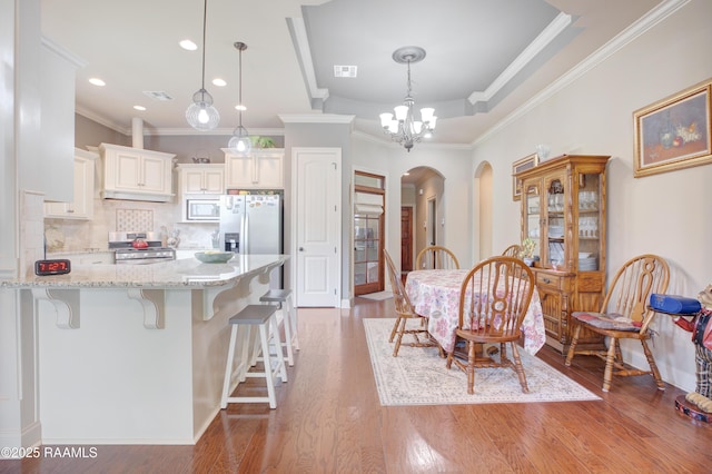 111 Grand Pointe Blvd, Lafayette, LA 70508 - kitchen featuring stainless steel appliances, arched walkways, a kitchen breakfast bar, a chandelier, and light stone counters