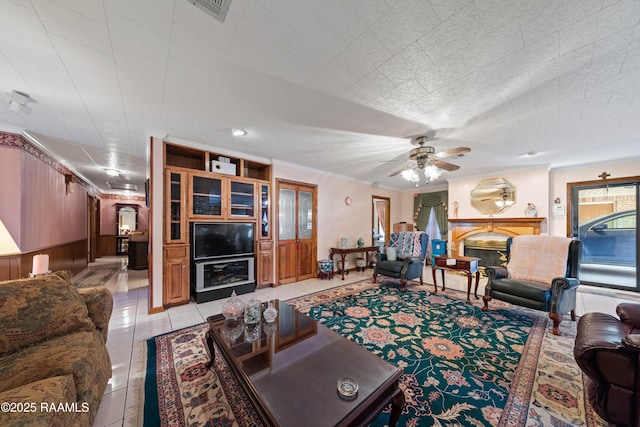 510 Monarch Dr, Lafayette, LA 70506 - living room featuring a ceiling fan, light tile patterned flooring, a glass covered fireplace, and wooden walls