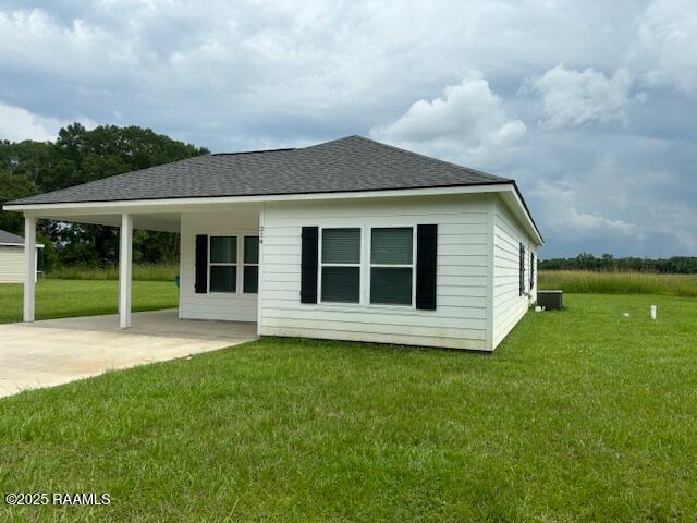 214 Dufilho Rd, Opelousas, LA 70570 - back of house with a shingled roof, a lawn, driveway, and a patio area