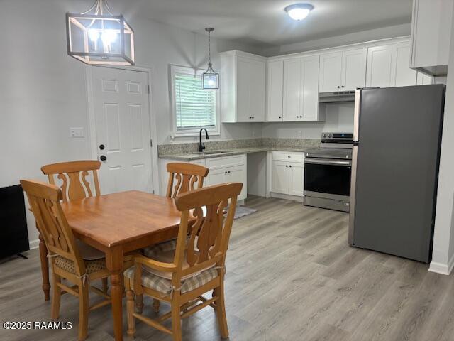 214 Dufilho Rd, Opelousas, LA 70570 - kitchen featuring stainless steel appliances, under cabinet range hood, a sink, white cabinets, and light wood-style floors