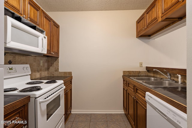 300 Lozes Ave Apt 1503, Lafayette, LA 70508 - kitchen featuring white appliances, a sink, brown cabinets, dark countertops, and tasteful backsplash