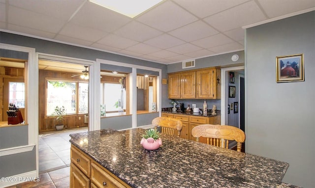 151 Hickory St, Port Barre, LA 70577 - kitchen featuring a drop ceiling, brown cabinetry, a ceiling fan, light tile patterned floors, and dark stone countertops