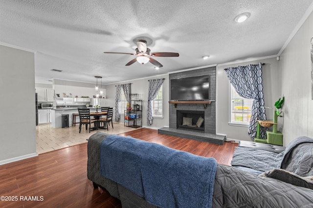 315 Creswell Ave, Scott, LA 70583 - living area with a ceiling fan, ornamental molding, wood finished floors, a textured ceiling, and a brick fireplace