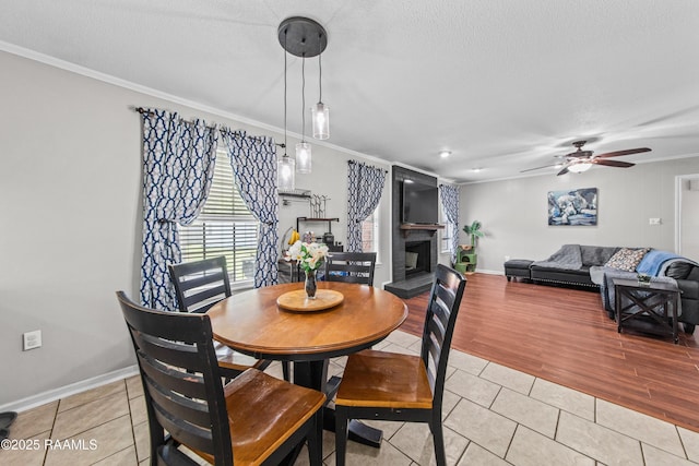 315 Creswell Ave, Scott, LA 70583 - dining room with crown molding, light tile patterned flooring, ceiling fan, a fireplace with raised hearth, and baseboards