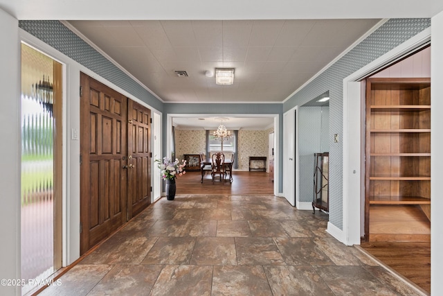 630 W Peach Ave, Eunice, LA 70535 - entrance foyer with wallpapered walls, ornamental molding, a chandelier, baseboards, and dark stone finish flooring