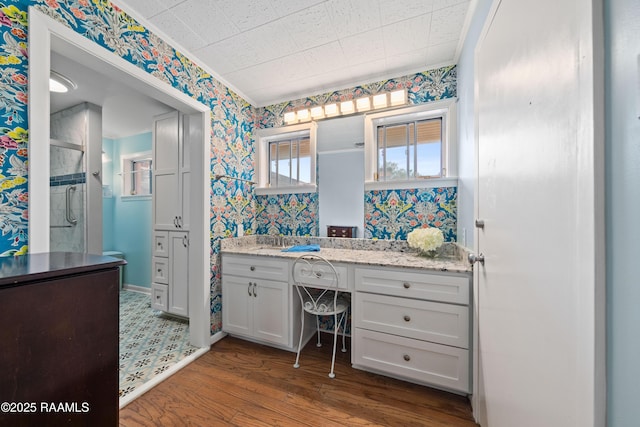 630 W Peach Ave, Eunice, LA 70535 - full bathroom featuring wallpapered walls, a shower stall, wood finished floors, and vanity