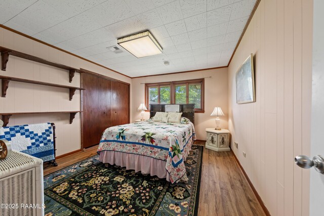 630 W Peach Ave, Eunice, LA 70535 - bedroom with wood finished floors, ornamental molding, baseboards, and wooden walls