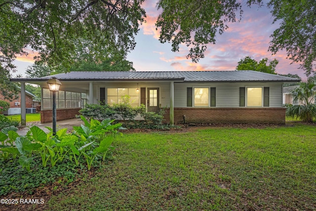 407 N Hebert Ave, Kaplan, LA 70548 - view of front facade with a lawn, brick siding, metal roof, and an attached carport