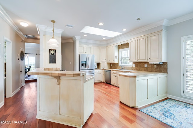 101 Hanover Sq, Lafayette, LA 70508 - kitchen with stainless steel appliances, a peninsula, tile counters, a skylight, and healthy amount of natural light