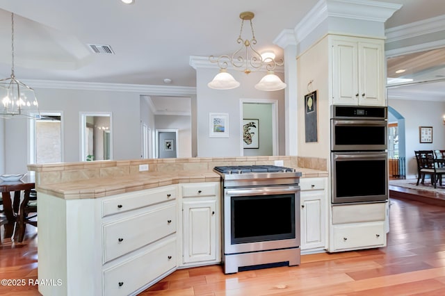 101 Hanover Sq, Lafayette, LA 70508 - kitchen with a chandelier, stainless steel appliances, tile counters, light wood-style floors, and ornamental molding