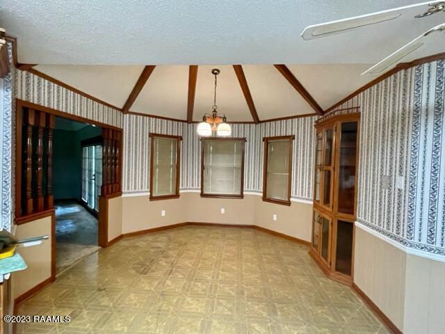 1944 Mills St, Scott, LA 70583 - unfurnished living room featuring vaulted ceiling, baseboards, tile patterned floors, wallpapered walls, and a textured ceiling
