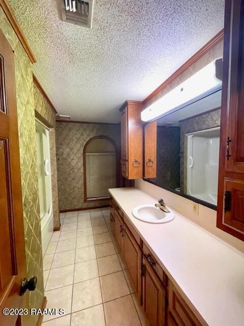1944 Mills St, Scott, LA 70583 - bathroom with wallpapered walls, a textured ceiling, tile patterned floors, vanity, and a shower