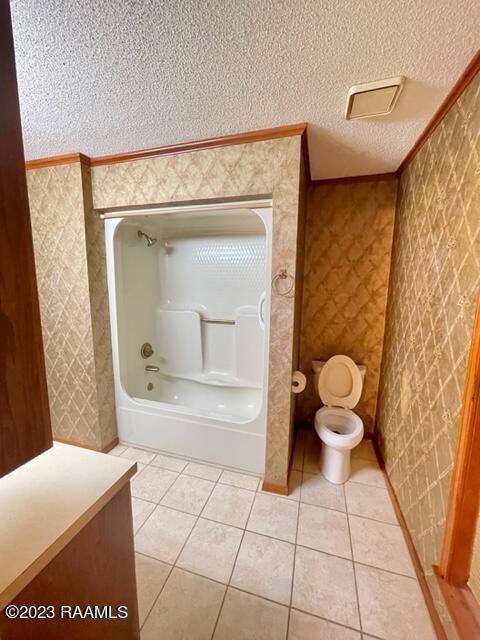 1944 Mills St, Scott, LA 70583 - bathroom featuring a textured ceiling, tile patterned floors, toilet, and wallpapered walls