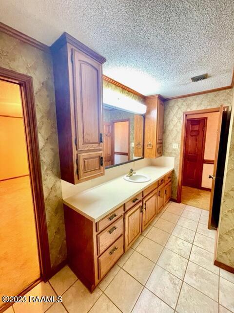 1944 Mills St, Scott, LA 70583 - bathroom with a textured ceiling, ornamental molding, vanity, and tile patterned flooring