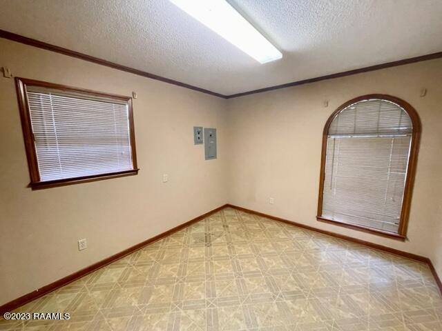 1944 Mills St, Scott, LA 70583 - unfurnished room with a textured ceiling, electric panel, light floors, crown molding, and baseboards