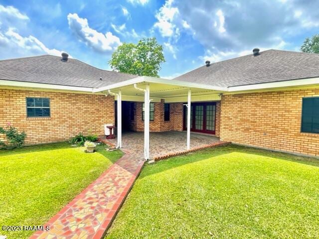 1944 Mills St, Scott, LA 70583 - back of property featuring a lawn, a patio, a shingled roof, and brick siding