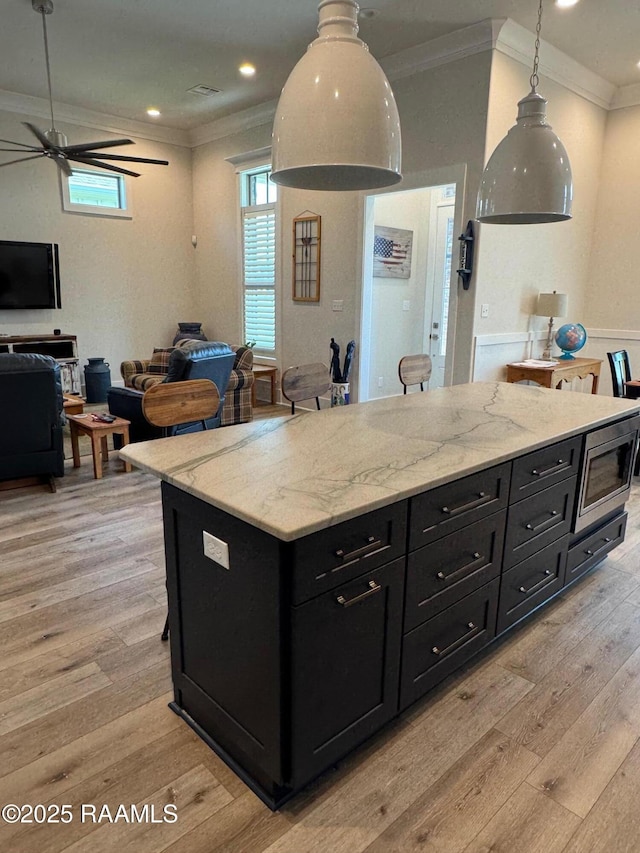 311 Villager Ave Unit C, Scott, LA 70583 - kitchen with dark cabinetry, crown molding, light wood-style floors, a ceiling fan, and stainless steel microwave