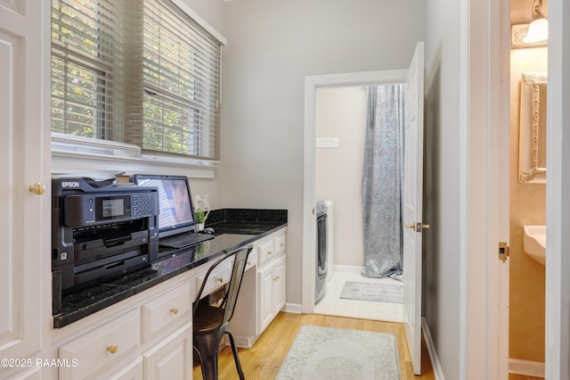 303 Duperier Ave, New Iberia, LA 70563 - kitchen with white cabinetry, light wood-style floors, washer / dryer, baseboards, and dark stone counters